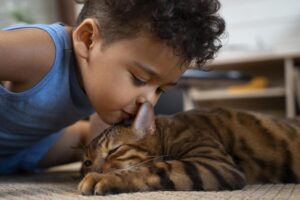 Menino beijando seu gato.