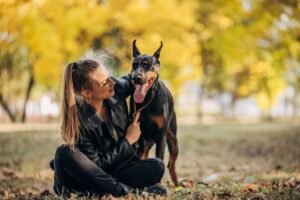 Mulher ao lado de um Doberman.