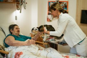 Gato de terapia visitando idosa acamada.