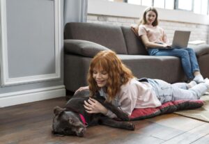 Mulher deitada no chão com cachorro.